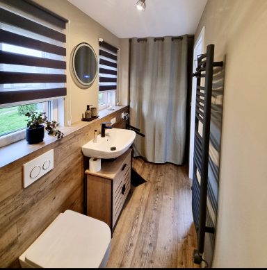 Modernes Badezimmer mit Holzdetails, Waschbecken und Handtuchheizkörper.
