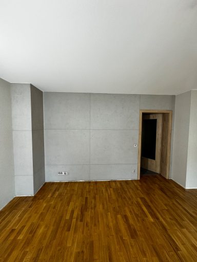 Leere Zimmer mit Betonwänden und einem Holzboden.