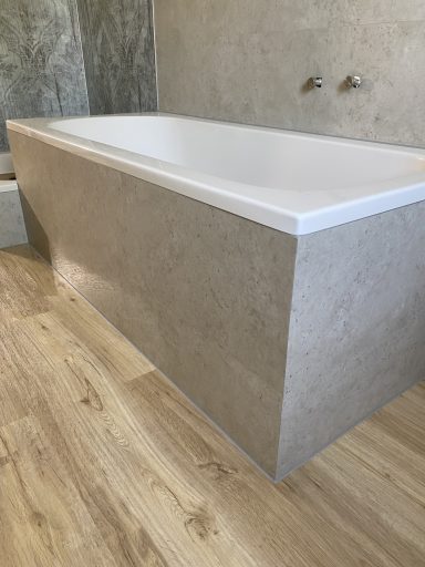 Moderne Badewanne mit schlichtem Design auf einem Holzboden.