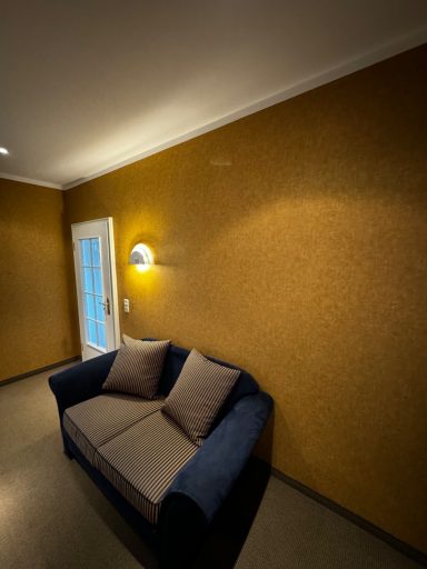 Blauer Sofa mit zwei Kissen vor orangem Wand und Fenster mit natürlichem Licht.