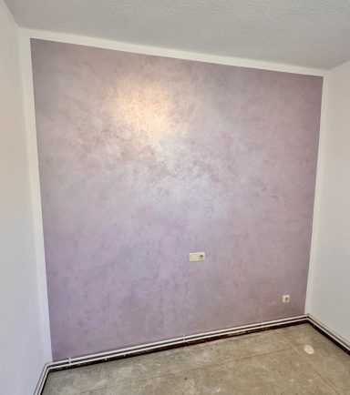 Lila gestrichene Wand in einem leeren Raum mit hellem Fußboden.