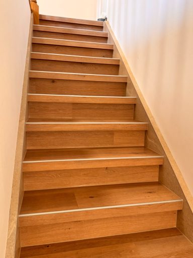 Holztreppe mit schlichten Stufen, die zu einem oberen Bereich führt.